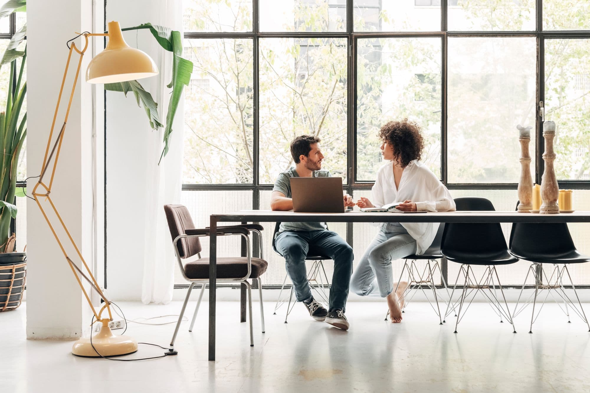 Two people talking over a laptop. 
